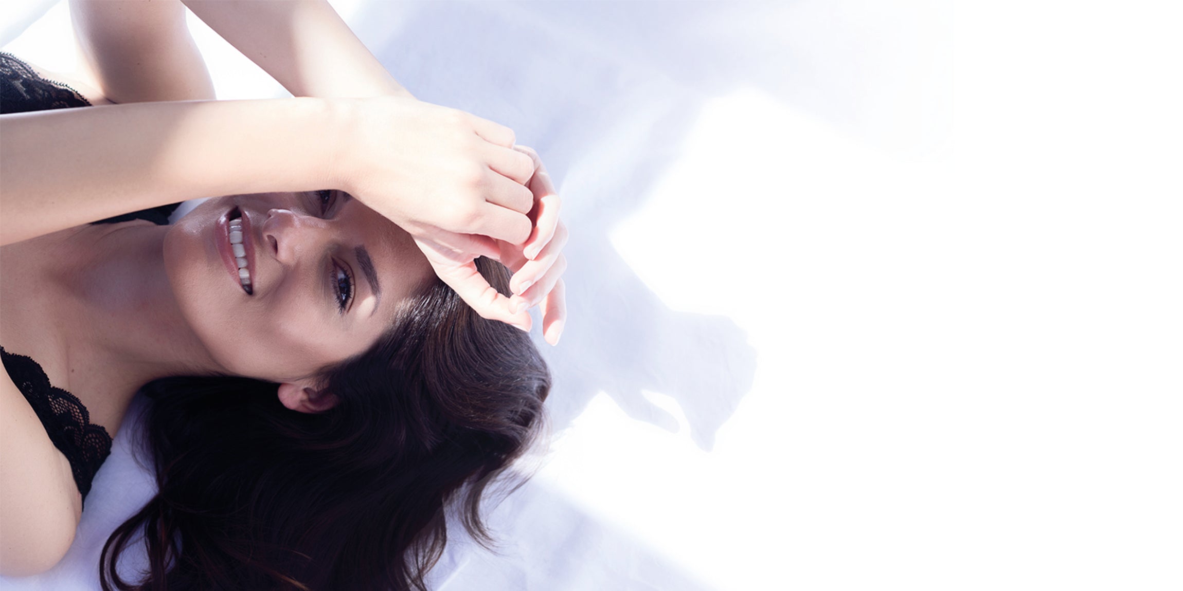 Frau posed vor einer weißen Wand mit den armen seitlich neben dem Gesicht verschränkt