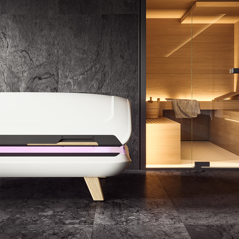 DAYON LightSpa, das Solarium für Zuhause, steht in einem Homespa-Ambiente vor einer schwarzen Marmorwand und einer Sauna mit Glastüren