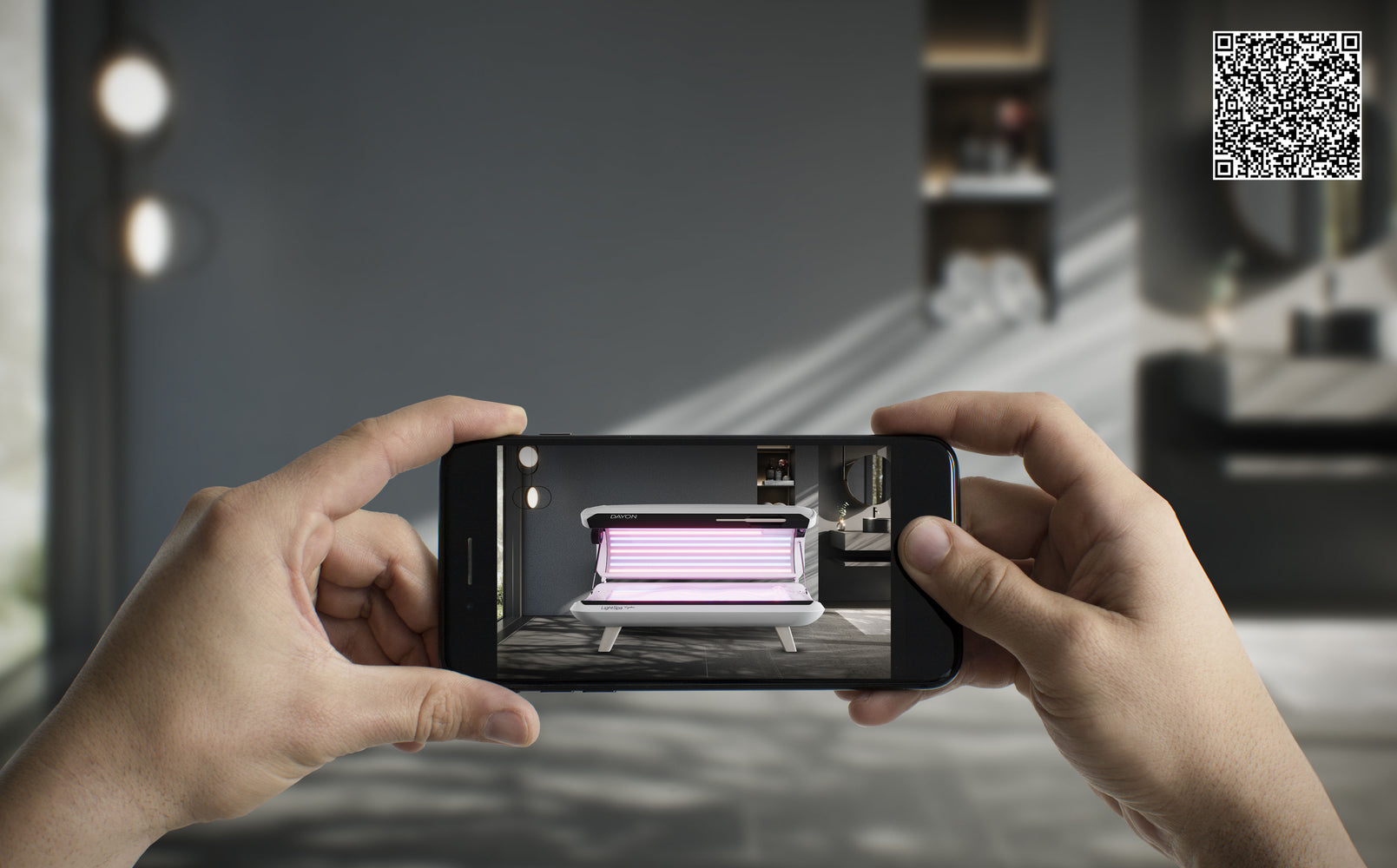 Hände mit Smartphone, dass das DAYON LightSpa Model zeigt wie es soeben via AR-Technologie in den Raum platziert wird, während sich im rechten oberen Eck der QR-Code für die aktive Anwendung dieser Visualisierung befindet 