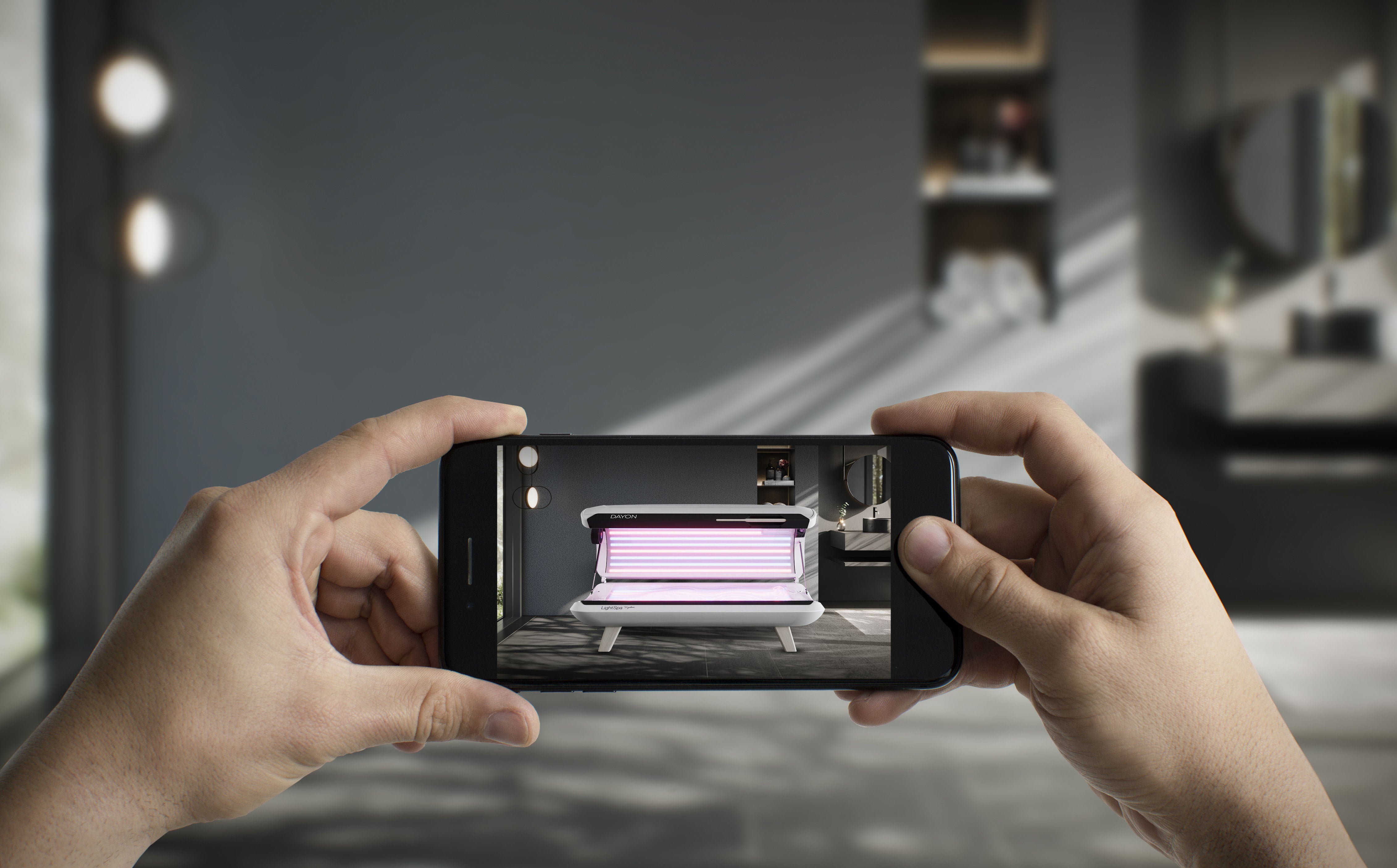 Hände mit Smartphone, dass das DAYON LightSpa Model zeigt wie es soeben via AR-Technologie in den Raum platziert wird