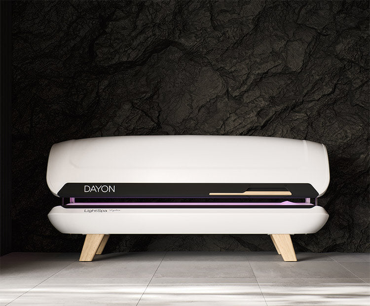DAYON LightSpa Heimsolarium Modell das auf einem weißen Boden und vor einer schwarzen edlen Wand aus Graphit steht